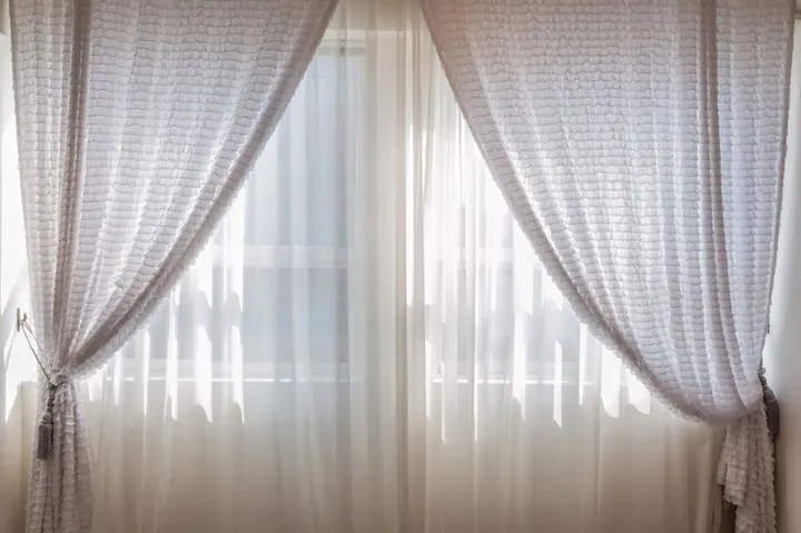 Cortinas blancas filtrando la luz del sol en una ventana