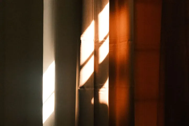 Luz de una tarde de verano entrando por una ventana con cortinas